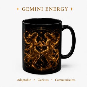 Op de afbeelding: Een zwarte keramische mok met een goudkleurige afbeelding van twee figuren die tegenover elkaar staan, omringd door hemelse patronen. De tekst GEMINI ENERGY staat erboven, met de woorden Adaptable, Curious en Communicative eronder.