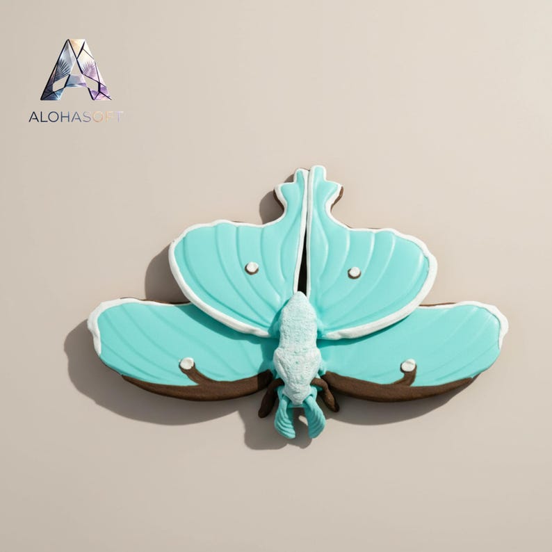 May include: A large, teal-colored moth-shaped cookie with white icing details and brown cookie base. The cookie has a detailed design, including a body and wing patterns. The cookie is likely a decorative treat.