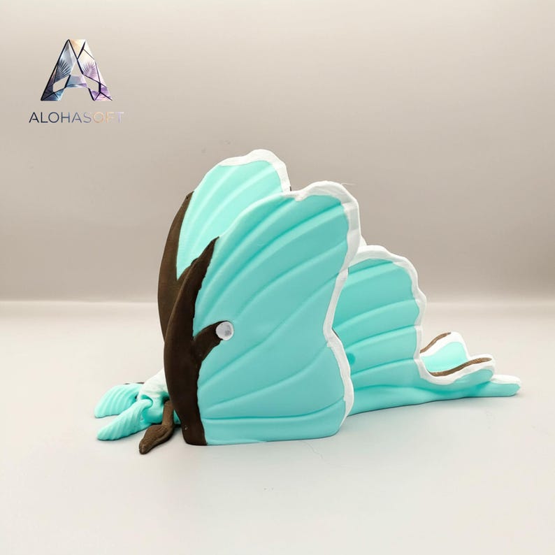 May include: A decorative butterfly sculpture in shades of turquoise, brown, and white. The butterfly has detailed wing patterns and a small, round accent. The sculpture is designed to sit flat on a surface.