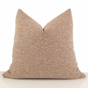 May include: A square decorative pillow in a neutral beige color. The pillow has a textured woven fabric and a classic shape, perfect for adding a touch of comfort and style to any living space. The pillow is approximately 20 inches square.