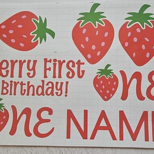May include: A sheet of stickers featuring a strawberry design. The stickers include red strawberries with green tops and the text "Berry First Birthday! One Name" in red. The strawberries have pink dots.