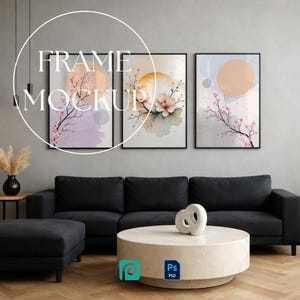 Puede incluir: Tres cuadros rectangulares en marcos negros con ilustraciones en acuarela de ramas de cerezo en flor y motivos solares circulares en tonos pastel suaves de rosa, melocotón y lavanda, expuestos sobre un sofá negro.