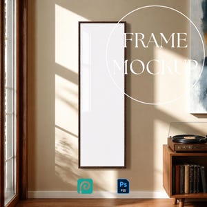 May include: A tall, rectangular vertical picture frame with a dark brown border and a blank white center. The frame is displayed on a plain wall, featuring the white text overlay FRAME MOCKUP and small blue icons for software file formats.
