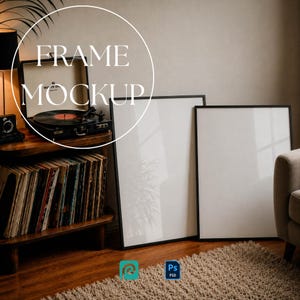 May include: Two vertical rectangular picture frames with thin black borders and white inserts, positioned next to a wooden record player stand containing a black turntable and a collection of vinyl records with the text FRAME MOCKUP.