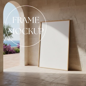 Może przedstawiać: Pusta makieta ramy z drewnianą ramą opiera się o teksturowaną ścianę. Tekst "FRAME MOCKUP" znajduje się w okręgu nad ramą. Scena jest na zewnątrz, z łukiem i widokiem na ocean.