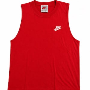 May include: A sleeveless red tank top with a crew neck. The Nike logo is printed in white on the upper left chest. A small Nike tag is visible near the neckline.