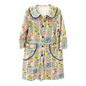 May include: A quilted long-sleeve coat featuring a patchwork pattern of pink, green, and yellow blocks with illustrated figures. The coat has a rounded collar, dark blue scalloped trim on the collar and pockets, and a front button closure.
