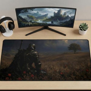 May include: A black gaming mouse pad featuring a knight in dark armor kneeling in a field with a tree and a castle in the background. A curved monitor, headphones, and a small plant are also on the desk.