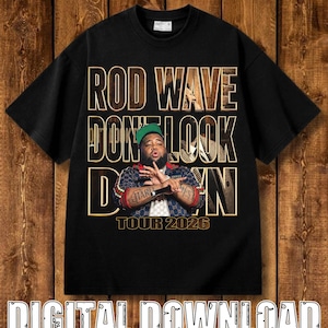 Puede incluir: Una camiseta negra de manga corta con un estampado gráfico de Rod Wave con una gorra verde y una chaqueta estampada. El texto dice ROD WAVE DON'T LOOK DOWN y TOUR 2026 en letras grandes con bordes dorados sobre una imagen fotográfica.