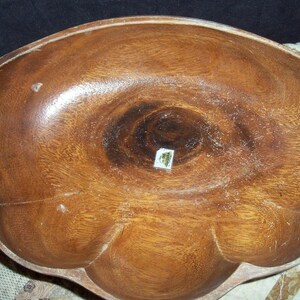 Peut inclure: Un grand bol en bois avec un bord festonn&eacute; unique. Le bol est fait d'un bois brun moyen chaud avec des motifs de grain visibles. L'int&eacute;rieur pr&eacute;sente un motif tourbillonnant plus fonc&eacute;. Une petite &eacute;tiquette est visible au centre.