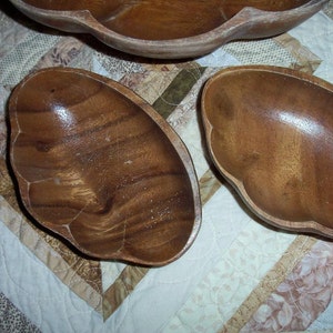 Peut inclure: Ensemble de bols de service en bois avec une finition naturelle. Les bols pr&eacute;sentent un bord festonn&eacute; unique. Le grain du bois est visible, ajoutant &agrave; l'esth&eacute;tique rustique. Les bols sont dispos&eacute;s sur une courtepointe &agrave; motifs.