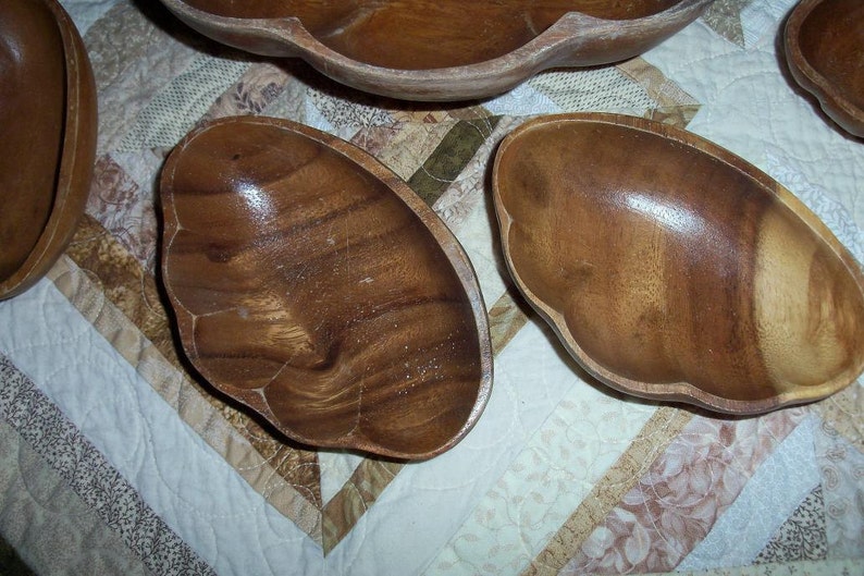 Peut inclure: Ensemble de bols de service en bois avec une finition naturelle. Les bols pr&eacute;sentent un bord festonn&eacute; unique. Le grain du bois est visible, ajoutant &agrave; l'esth&eacute;tique rustique. Les bols sont dispos&eacute;s sur une courtepointe &agrave; motifs.