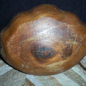 Peut inclure: Un grand bol en bois avec une finition marron chaud. Le bol a une forme organique avec un int&eacute;rieur large et peu profond. Les rayures et l'usure ajoutent du caract&egrave;re &agrave; la pi&egrave;ce artisanale. Probablement utilis&eacute; pour servir ou exposer. Diam&egrave;tre d'environ 30 cm.