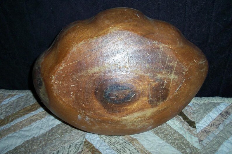 Peut inclure: Un grand bol en bois avec une finition marron chaud. Le bol a une forme organique avec un int&eacute;rieur large et peu profond. Les rayures et l'usure ajoutent du caract&egrave;re &agrave; la pi&egrave;ce artisanale. Probablement utilis&eacute; pour servir ou exposer. Diam&egrave;tre d'environ 30 cm.