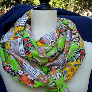 May include: A colorful patchwork scarf with a green, yellow, brown, and white plaid pattern. The scarf is made of fabric with a floral print and is tied in a knot.