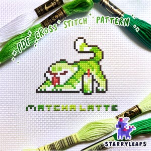 May include: A cross-stitch pattern featuring a green pixelated creature with a red tongue, labeled "Matcha Latte." The image includes green and white embroidery floss, with the text "PDF Cross Stitch Pattern" and a logo for StarryLeaps.