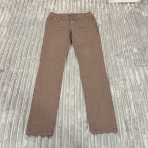 May include: A pair of dusty rose-colored jeans. The jeans have a classic five-pocket design, a button and zipper closure, and a straight leg cut. The pants are made of a medium-weight fabric and appear to be new.