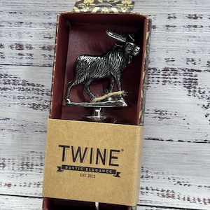 May include: A silver-colored moose bottle stopper displayed in a decorative box. The box is brown with the text "TWINE RUSTIC ELEGANCE EST. 2012". The stopper is made of metal and has a detailed design.