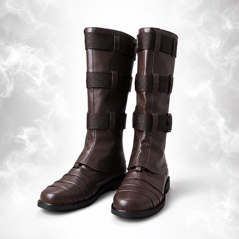 May include: A pair of dark brown mid-calf boots featuring a smooth finish on the lower foot section and three horizontal fabric straps with buckles along the shaft. The boots have a rounded toe design and a flat sole, providing a structured appearance.