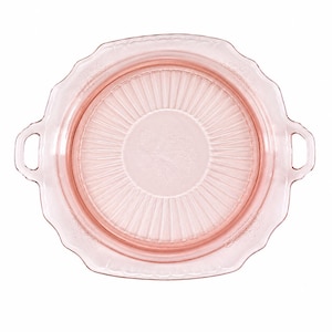 Può includere: Un piatto da portata in vetro rosa con bordo smerlato e due manici. Il centro del piatto presenta un design strutturato e scanalato. Il piatto è circolare e sembra essere vintage.