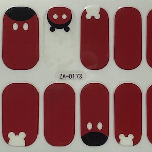May include: Sheet of red nail wraps featuring white and black cartoon character designs. The nail wraps have a glossy finish and are arranged in rows. The text "ZA-0173" is printed on the sheet.