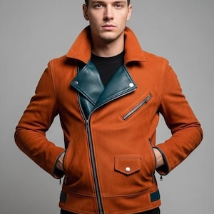 Op de afbeelding: Een roestkleurige leren jas met een blauwgroene revers en accenten. De jas heeft een ritssluiting, meerdere zakken en een klassiek bikerjack-ontwerp. Het model draagt er een zwart shirt onder.