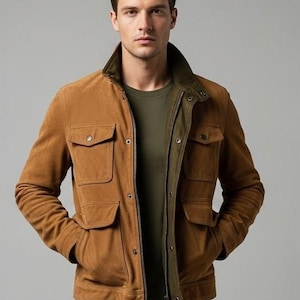 Puede incluir: Chaqueta de ante marrón con cuatro bolsillos delanteros y cuello verde oscuro. La chaqueta tiene cierre de cremallera y se lleva sobre una camisa verde. El modelo lleva vaqueros azul oscuro.