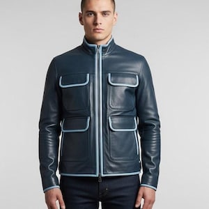 May include: A navy blue leather jacket with four front pockets and a zip-up closure. The jacket features light blue trim along the pockets, zipper, collar, and cuffs. The jacket is worn with dark blue jeans.