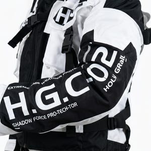 Pu&ograve; includere: Giacca da moto bianca e nera con la scritta "H.G. CO2 HOLY GRAIL" sulla manica. La giacca ha un design moderno con pi&ugrave; cinghie e un colletto alto. Progettata per la protezione da condizioni meteorologiche estreme.