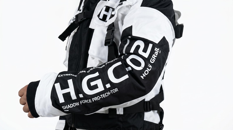 Pu&ograve; includere: Giacca da moto bianca e nera con la scritta "H.G. CO2 HOLY GRAIL" sulla manica. La giacca ha un design moderno con pi&ugrave; cinghie e un colletto alto. Progettata per la protezione da condizioni meteorologiche estreme.