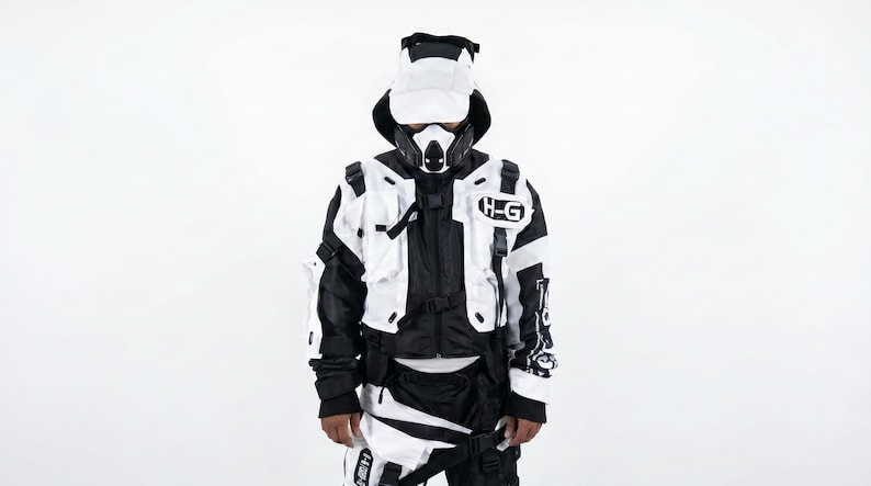 Pu&ograve; includere: Un completo futuristico in bianco e nero con cappellino e maschera abbinati. La giacca ha pi&ugrave; tasche e la scritta "H-G" sul petto. L'outfit &egrave; progettato con un'estetica tattica.