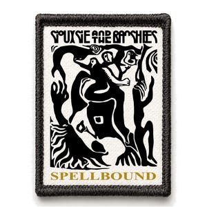 May include: A rectangular patch with a black border and a white background. The patch features a black and gold graphic design with the text "SIOUXSIE AND THE BANSHEES" at the top and "SPELLBOUND" at the bottom. The design includes abstract figures.