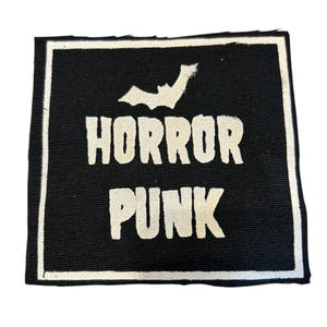 May include: A black rectangular patch with a white border. The words "HORROR PUNK" are printed in bold, white letters, with a white bat graphic above the word "HORROR".