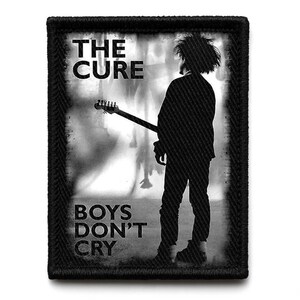 Puede incluir: Parche en blanco y negro con la banda "The Cure". El parche muestra la silueta de una persona tocando la guitarra, con el texto "THE CURE" arriba y "BOYS DON'T CRY" abajo. El parche tiene un borde negro.