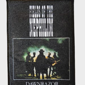 Może przedstawiać: Czarna prostokątna naszywka z białym napisem "FIELDS OF THE NEPHILIM". Poniżej znajduje się oprawiony obraz sylwetek. Słowo "DAWNRAZOR" jest wydrukowane na dole naszywki na biało.