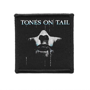May include: Black square patch with the text "TONES ON TAIL" in light blue. The patch features a white and light blue graphic design of a figure. The patch has a black border.