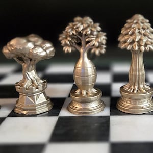 May include: A chess set with metallic tree-shaped pieces. The pieces are arranged on a black and white checkered board. The pieces vary in size and design, with intricate details.