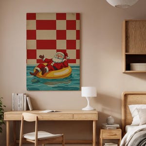 Puede incluir: Una impresión en lienzo enmarcada representa a Papá Noel relajándose en una piscina sobre un flotador inflable amarillo. Viste un traje y gorro rojos. El fondo es un patrón de cuadros rojos y blancos. El agua es azul.