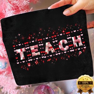 Op de afbeelding: Zwarte rechthoekige mat met het woord "TEACH" in een patchwork-ontwerp van rode en witte harten en patronen. Rode en roze harten en sterren omringen het woord. Een gouden zegel met tekst staat in de rechter benedenhoek.