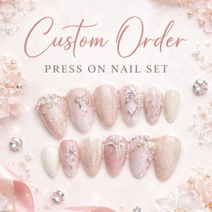 May include: A custom press-on nail set with a soft pink and glittery design. The set includes various nail shapes, some adorned with rhinestones and floral accents. The image features the text "Custom Order" and "Press On Nail Set".