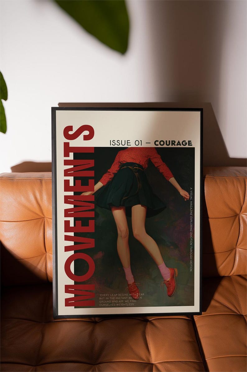 May include: A framed poster with the word "MOVEMENTS" in large red letters. The poster features a person in a red top and dark skirt, with the text "ISSUE 01 - COURAGE". The poster is on a brown leather couch.