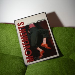 May include: A magazine titled "MOVEMENTS" with the text "ISSUE 05 - COURAGE" on a green couch. The magazine cover features a person wearing black pants, orange shoes, and pink socks. The magazine has a black border.