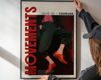 May include: A framed poster with the word "MOVEMENTS" in large red letters. The poster features a person in black pants and orange shoes. The text "ISSUE 05 - COURAGE" is also visible. The poster is being held by a person.