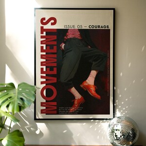 May include: A framed poster with the word "MOVEMENTS" in large red letters. The poster features a person in a pink shirt, black pants, and orange shoes. Text on the poster reads "ISSUE 05 - COURAGE" and a quote about fear and weightlessness.