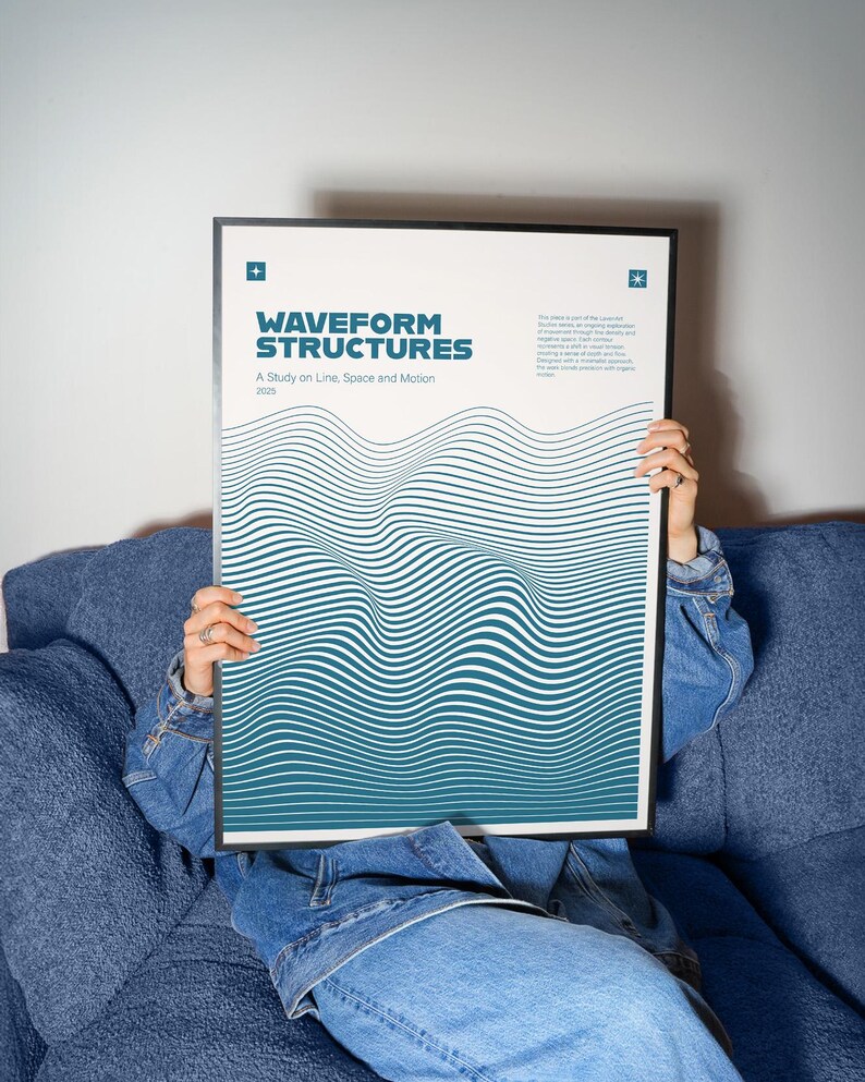 May include: A framed poster with the title "WAVEFORM STRUCTURES" in teal and white, featuring a wavy line design. The poster is held by a person wearing a denim jacket and jeans, sitting on a blue sofa.