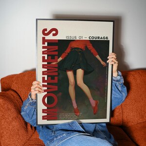 May include: A framed magazine cover with the word "MOVEMENTS" in red. The cover features an illustration of a person in a red top and black skirt. The text "ISSUE 01 - COURAGE" is also visible.