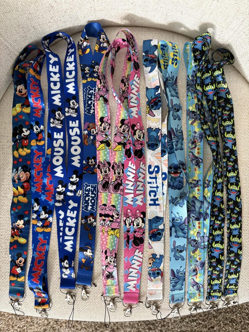 May include: A selection of vibrant lanyards showcasing cartoon characters. Designs include Mickey Mouse, Minnie Mouse, and Stitch, with text such as "MICKEY" and "MINNIE". The lanyards have metal clasps and are suitable for holding keys or ID badges.