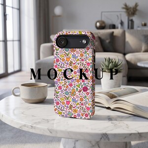 Könnte beinhalten: Ein Handyhülle mit einem farbenfrohen Blumenmuster mit Herzen, Blumen und Schmetterlingen auf hellrosa Hintergrund. Das Wort "MOCKUP" ist schwarz auf der Vorderseite aufgedruckt. Die Hülle liegt auf einem weißen Marmortisch.