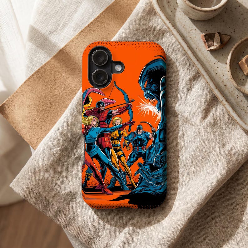 Peut inclure: Coque de t&eacute;l&eacute;phone orange avec une illustration de bande dessin&eacute;e de super-h&eacute;ros combattant un monstre bleu. Les h&eacute;ros sont en pleine action, avec des arcs et des fl&egrave;ches. La coque a un objectif de cam&eacute;ra noir.
