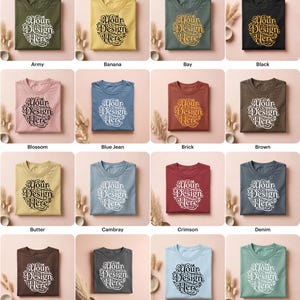 May include: A collection of folded t-shirts in various colors, each featuring the text "Your Design Here" in a circular design. Colors include army green, yellow, black, pink, blue, brown, and others.